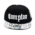 Nahaufnahme der Compton-Stickerei und der grauen Schlangenhaut-Textur auf einem Snapback - Verstellbar / Schwarz mit Schlangenmuster