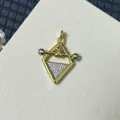 Makrofoto des goldenen Meerjungfrau-Anhängers mit Zirkonia-Besatz und geometrischem Rahmen - Trapez Hantel Geometrisch