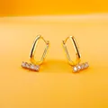 Gold rectangular U-shaped hoop earrings with micro-set cubic zirconia on orange background - U-Shaped Bar Five Zirconia Style