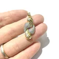 Handheld view of elegant gold-plated S-curve pendant with sparkling cubic zirconia inlay - S-Curve Style
