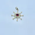 Macro shot of sunburst gold pendant featuring a ruby center and orange gemstones - Red Gemstone Starburst Style / Gold
