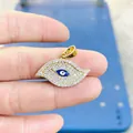 Handheld view of a gold Evil Eye pendant with white cubic zirconia and blue enamel center - Gold