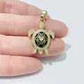 Detailansicht eines Schildkrötenanhängers mit Zirkonia und schwarzer Emaille auf der Hand - Goldene Schildkröte (Schwarze Emaille Herz)