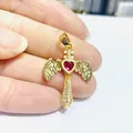 Macro detail of gold cross pendant with red heart gemstone and winged zircon wings - Golden Red Heart Cross