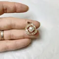 Detail showing a gold flower pendant with white pearl and zircon held on a finger for scale - Radiant Sunflower Style (Gold No. 4)