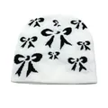 Texture de tricot détaillée du bonnet blanc avec motif jacquard à nœuds noirs d'hiver - Taille unique / Blanc