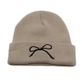 Close-up of beige knit beanie featuring detailed black bow embroidery on the folded brim - One Size / Dark Khaki