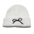 Close-up of black bow embroidery detail on soft white ribbed knit winter beanie hat - One Size / White