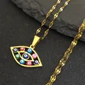 Macro view of gold stainless steel necklace with colorful evil eye charms on dark stone - Water Wave Chain Style / Gold