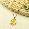 Gold stainless steel necklace with round coin zodiac relief pendant on a woven mat - Gemini