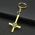 Detail of a golden metal inverted cross keychain with pentagram cutout on black texture - Gold