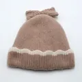 Close-up of kids' ribbed knit hat with a bow detail and wavy pattern in beige and tan - Light Coffee