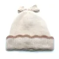 Detailed view of cream knit beanie with brown wavy patterns and large bow decoration - Off White