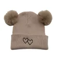 Close-up of beige knit hat featuring double fluffy pom poms and heart embroidery - One Size / Khaki