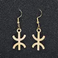 Macro detail of gold Berber Yaz symbol earrings on a textured black backdrop - Gold