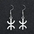 Detailed view of silver stainless steel Berber Yaz symbol drop earrings on dark background - Silver