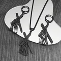 Close-up of black stainless steel cross pendant and earrings on a reflective mirror surface - Black