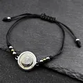 Handmade woven Saint Benedict rope bracelet with gold and silver beads on a stone surface - Silver