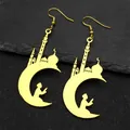 Gros plan détaillé de boucles d'oreilles lune et mosquée dorées sur pierre sombre - Boucles d'oreilles / Or
