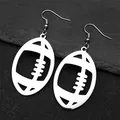 Detail shot of silver hollow American football earrings on a textured slate surface - Earrings Only / Silver Ear Hooks