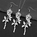 Détails de l'ensemble pendentif rose et boucles d'oreilles en acier sur fond de pierre - Collier Et Boucles d'Oreilles Argentés