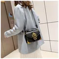 Outdoor shot of black leather crossbody bag with golden lion head hardware and metal corners - Black