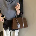 Dunkelbraune Vintage-Handtasche aus Wildleder mit Tragegriffen und dekorativem Lederanhänger - Braun