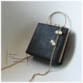 Detail of black square evening bag with gold trim, ring handle and pearl chain charm - Simple Version / Black