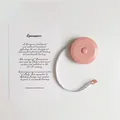 Macaron pink retractable sewing tape measure for body measurement on white surface - Pink