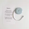 Detailed view of a mini blue retractable measuring tape with a decorative art card - Blue