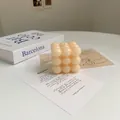 Détail macro d'une bougie cube en cire de soja avec livre et carte décorative - Bubble Cube Ivoire (Crème Vanille)