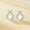 Elegant silver pearl earrings with micro-pave zirconia wrap on beige stone background - Cross Pearl Stud Earrings (ED198)