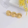 Detailed view of golden shell hair clip with glossy metal finish and textured fan design - Gold Shell Style