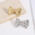 Bow-shaped metal brooch with hammered texture in gold and silver finish on stone - Silver-Tone Bowknot Style