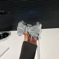 Primer plano de un bolso de lazo plateado en acrílico efecto espejo con asa de cadena - Forma de Lazo / Plateado