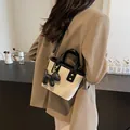 Beige bucket bag with black trim and puppy charm shown on model in a cafe setting - 19*9*16 / Dark Brown