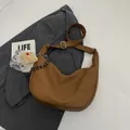 Detail einer braunen Hobo-Tasche mit Toast-Plüschanhänger und gewebtem Tragegurt - Braun