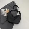 Detail der schwarzen Hobo-Tasche mit Litschistruktur auf grauem Sakko mit Silberteilen - Schwarz