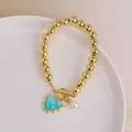 Detail of 18K gold beaded bracelet with blue heart pendant and freshwater pearl with OT clasp - Lake Green