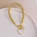 Detail of 18K gold OT buckle bracelet with heart pendant and water drop pearl - White