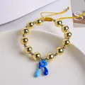 Detalle macro de cuentas de oro 18K y dije de letra R esmaltada en pulsera tejida - Letra R