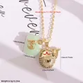 Detail van 18K vergulde ketting met jade geldzakje en gelukskat hangers op een witte schaal - Lichtgroen