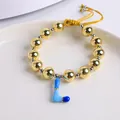 Detalle de pulsera de cuentas de oro 18K con colgante letra L en esmalte azul y cordón - Letra L