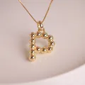 Macro detail of 18K gold plated letter P balloon pendant on a minimalist chain - Letter P