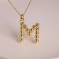 Detailed view of an 18K gold-plated M letter pendant with unique beaded metal texture - Letter M