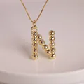 Macro shot of polished 18K gold-plated letter N pendant with unique beaded design - Letter N