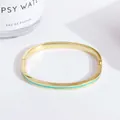 Close-up of 18K gold plated copper bangle with turquoise enamel inlay and hinge detail - Lake Green
