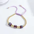Detail of 18K gold beads and purple evil eye charms on an adjustable braided bracelet - Purple
