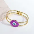 Detail eines 18K vergoldeten Armreifs mit lila Auge der Medusa und Doppelschicht-Rahmen - Lila