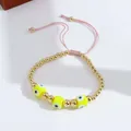 Detail of adjustable evil eye bracelet with golden beads and pink braided cord closure - Yellow